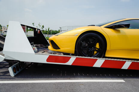 yellow sports car half way loaded onto a tilt tray hire tow truck