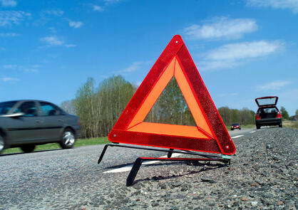 close up view of a hazard triangle on the road with a car passing at speed