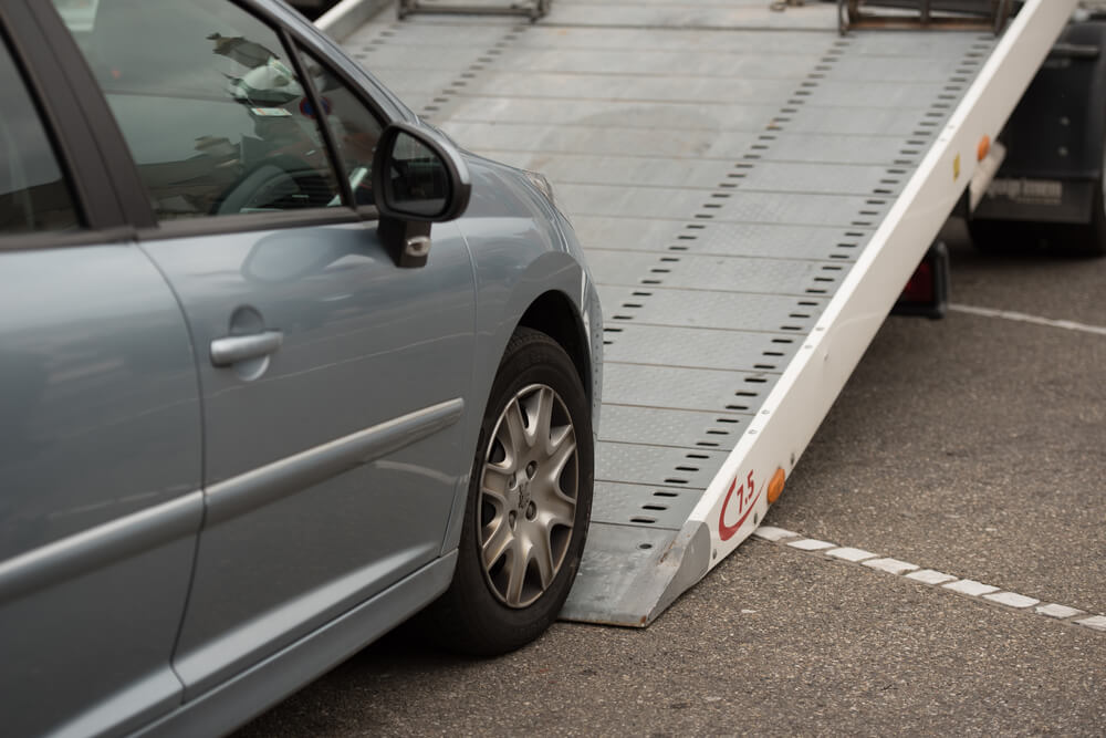 family car being loaded onto a tilt tray hire tow truck